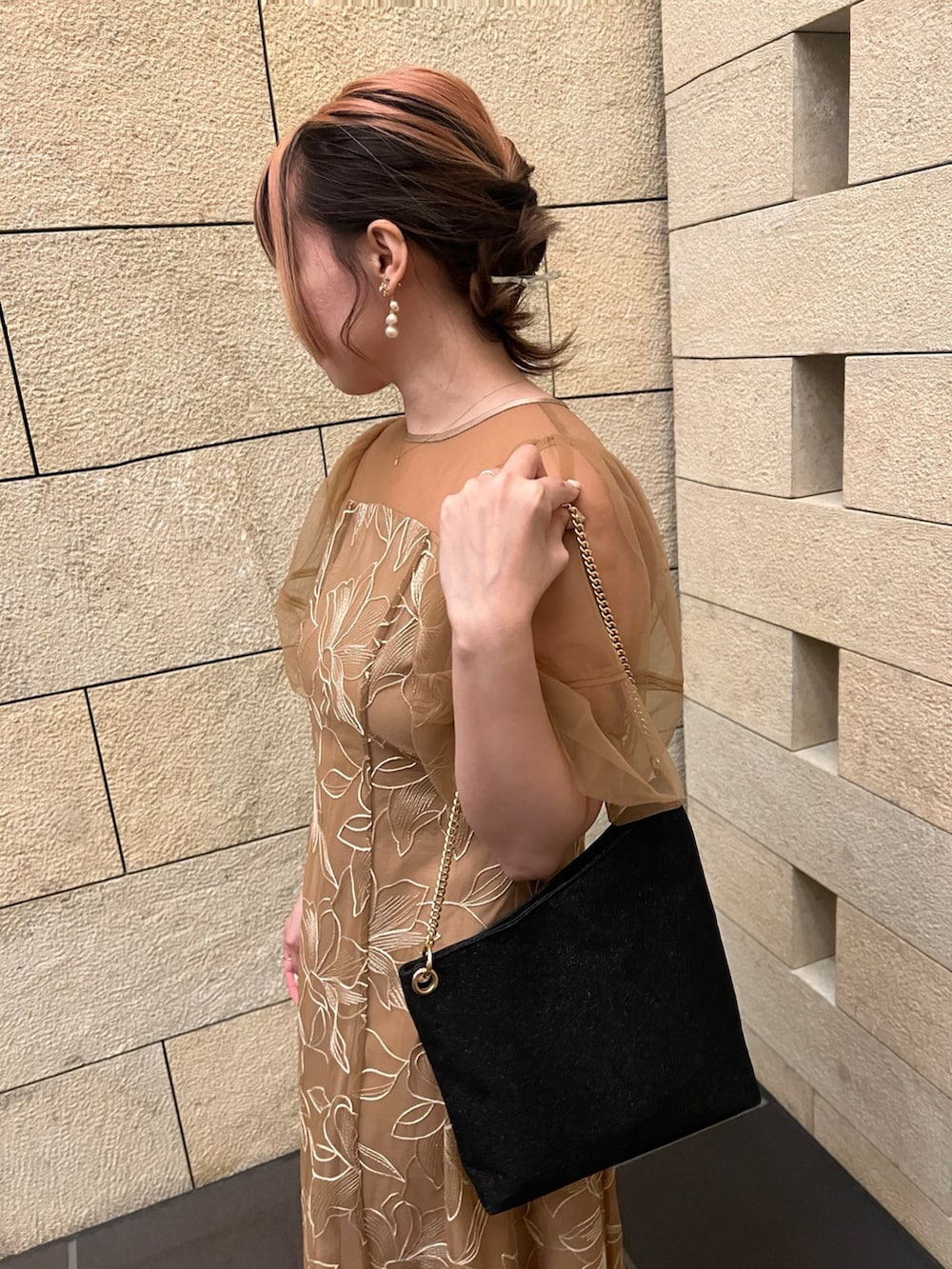 オレンジ系のドレス、ブラック系のパンプス、ブラック系のショルダーバッグを着用したレディースの春コーディネートの5枚目の写真