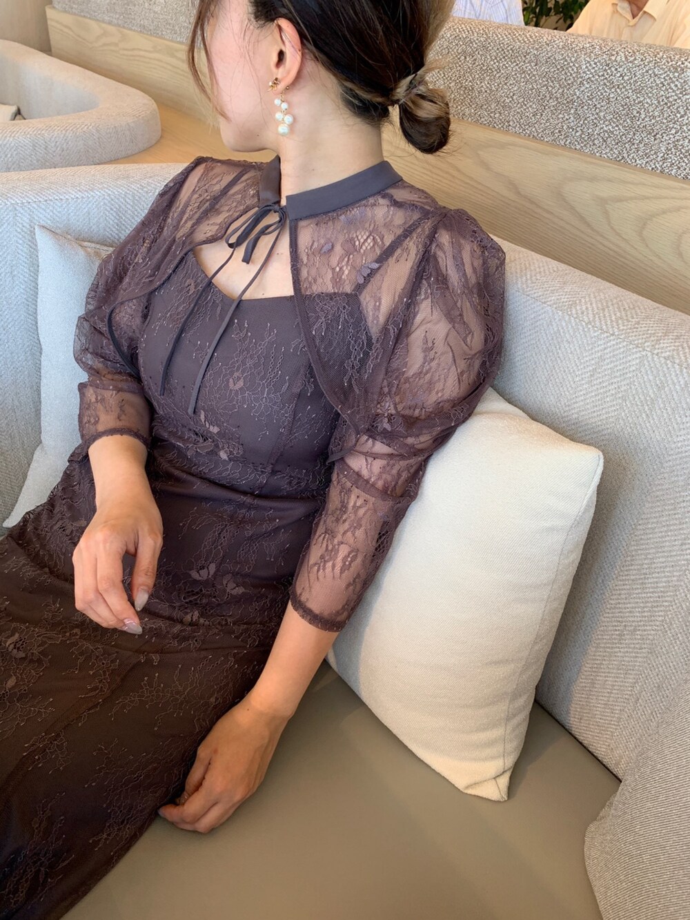 グレー系のドレス、ゴールド系のショルダーバッグ、ゴールド系のピアス（両耳用）を着用したレディースの夏コーディネートの3枚目の写真