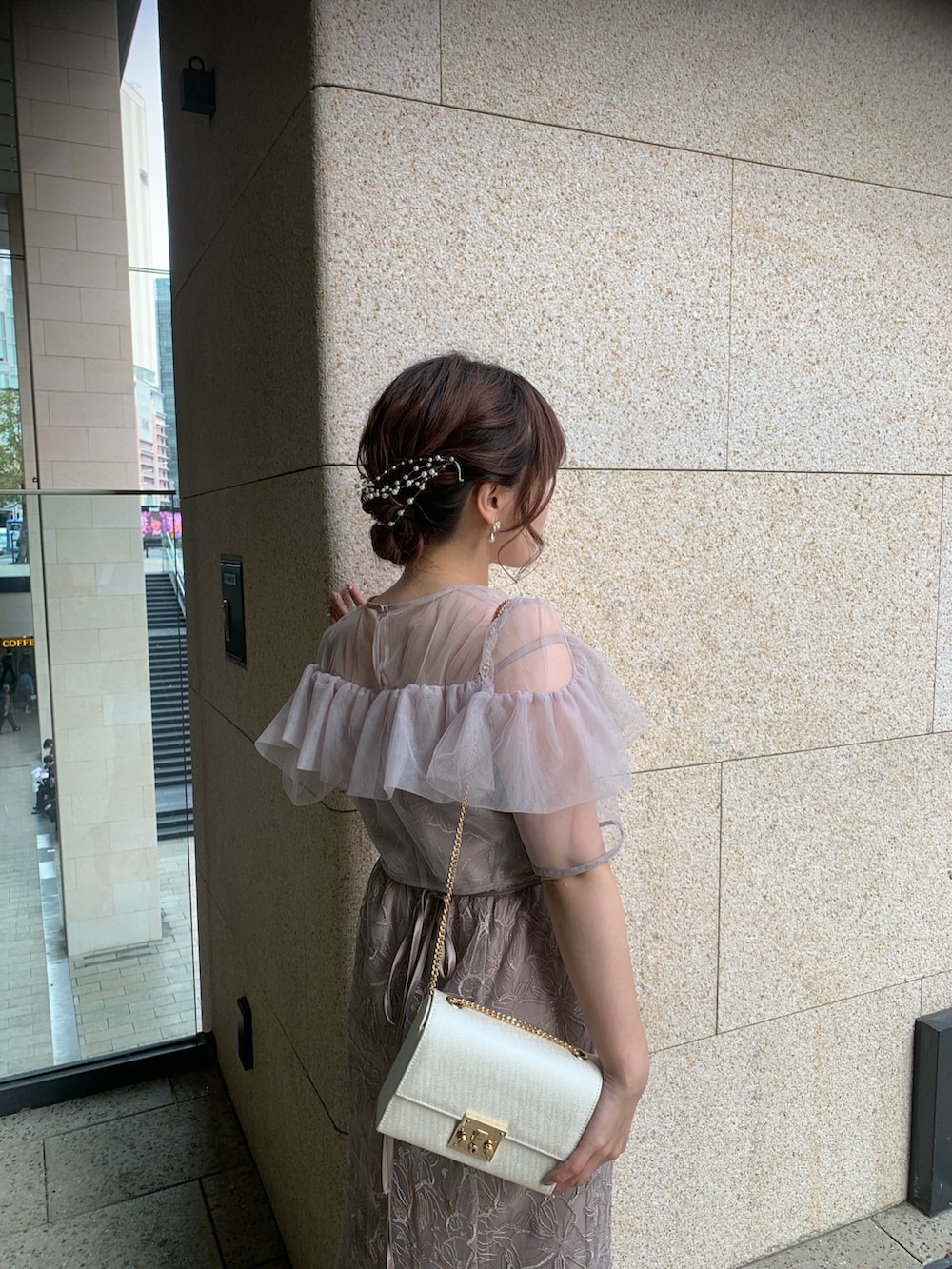 ベージュ系のドレス、ベージュ系のクラッチバッグ、ゴールド系のヘアピンを着用したレディースの春コーディネートの6枚目の写真
