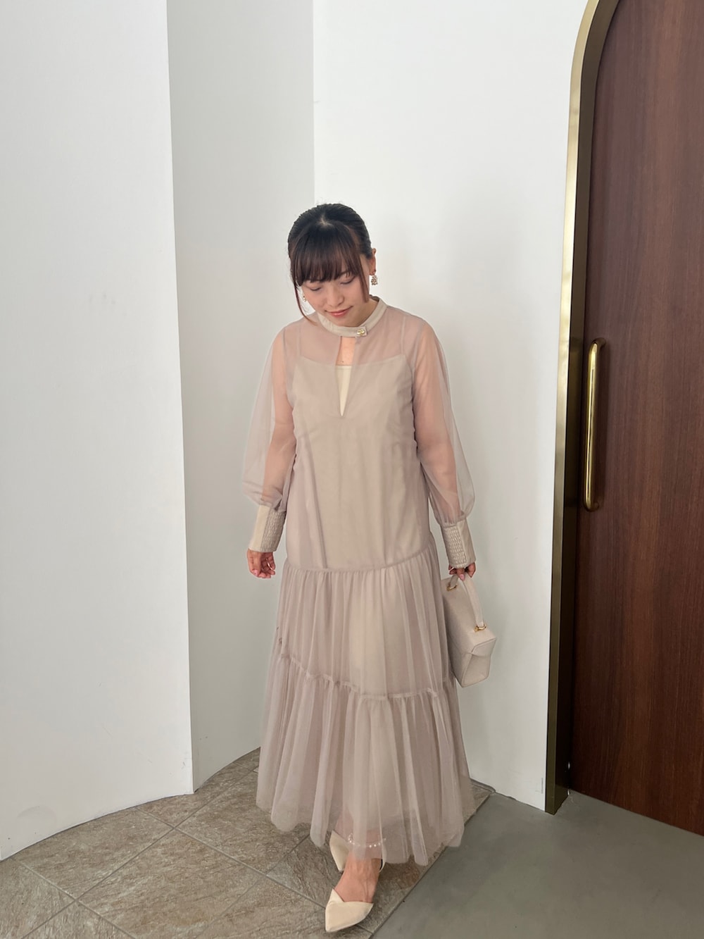 ベージュ系のドレス、ゴールド系のハンドバッグ、ベージュ系のシューズを着用したレディースの秋コーディネートの8枚目の写真