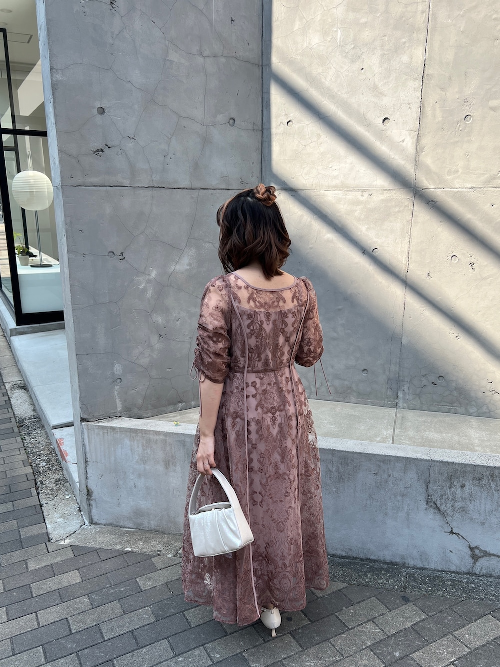 ピンク系のドレス、ベージュ系のハンドバッグ、ベージュ系のシューズを着用したレディースの春コーディネートの3枚目の写真