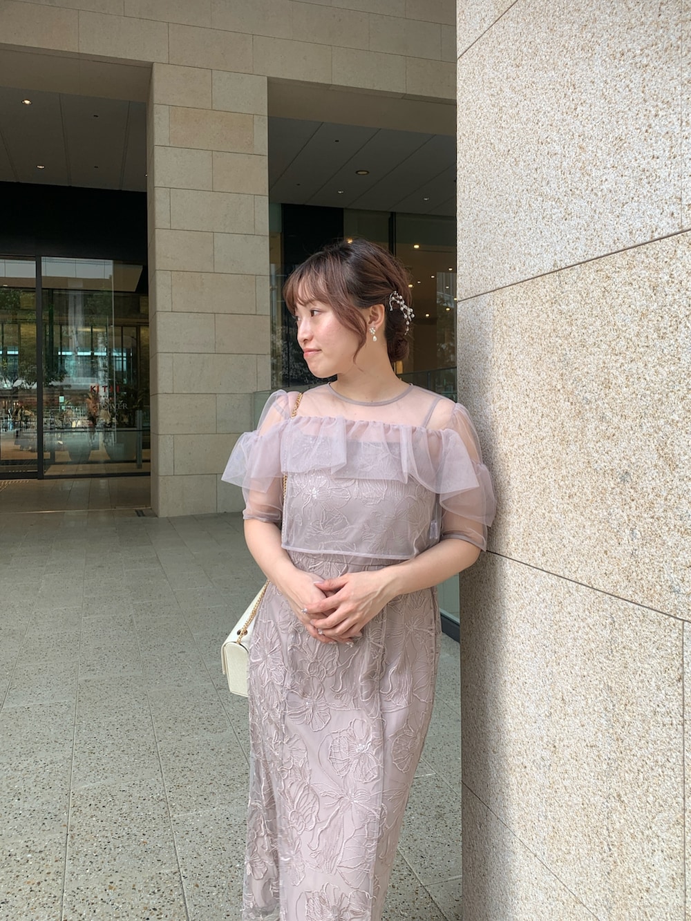 ベージュ系のドレス、ベージュ系のクラッチバッグ、ゴールド系のヘアピンを着用したレディースの春コーディネートの5枚目の写真