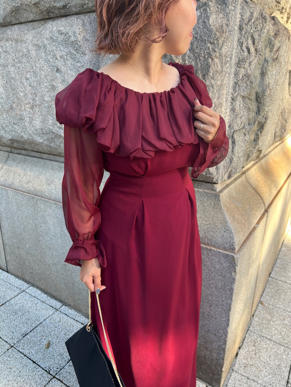 レッド系のドレス、ブラック系のショルダーバッグ、ブラック系のパンプスを着用したレディースの秋コーディネートの2枚目の写真