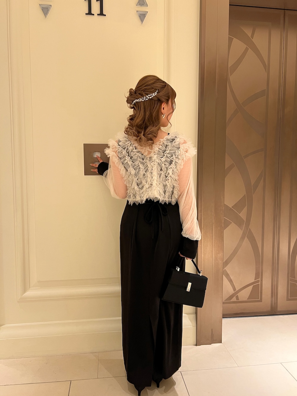 ブラック系のドレス、ブラック系のハンドバッグ、ゴールド系のヘアピンを着用したレディースの春コーディネートの4枚目の写真