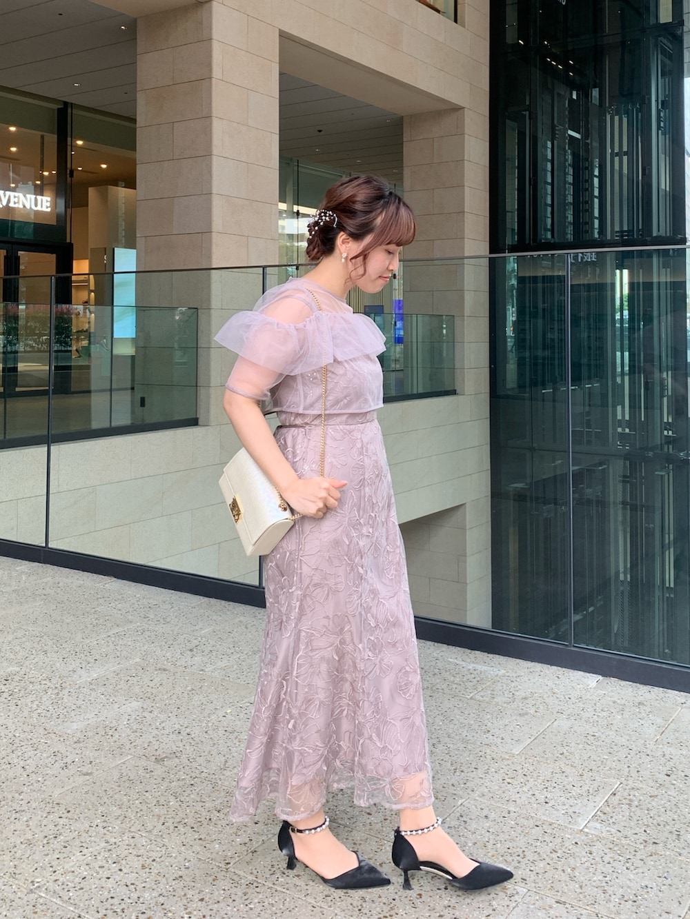 ベージュ系のドレス、ベージュ系のクラッチバッグ、ゴールド系のヘアピンを着用したレディースの春コーディネートの3枚目の写真