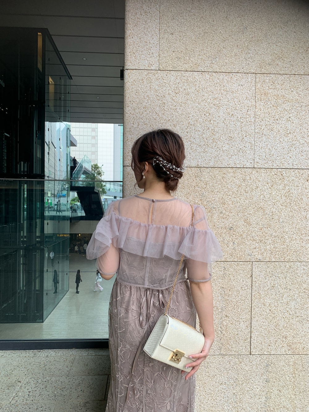 ベージュ系のドレス、ベージュ系のクラッチバッグ、ゴールド系のヘアピンを着用したレディースの春コーディネートの7枚目の写真