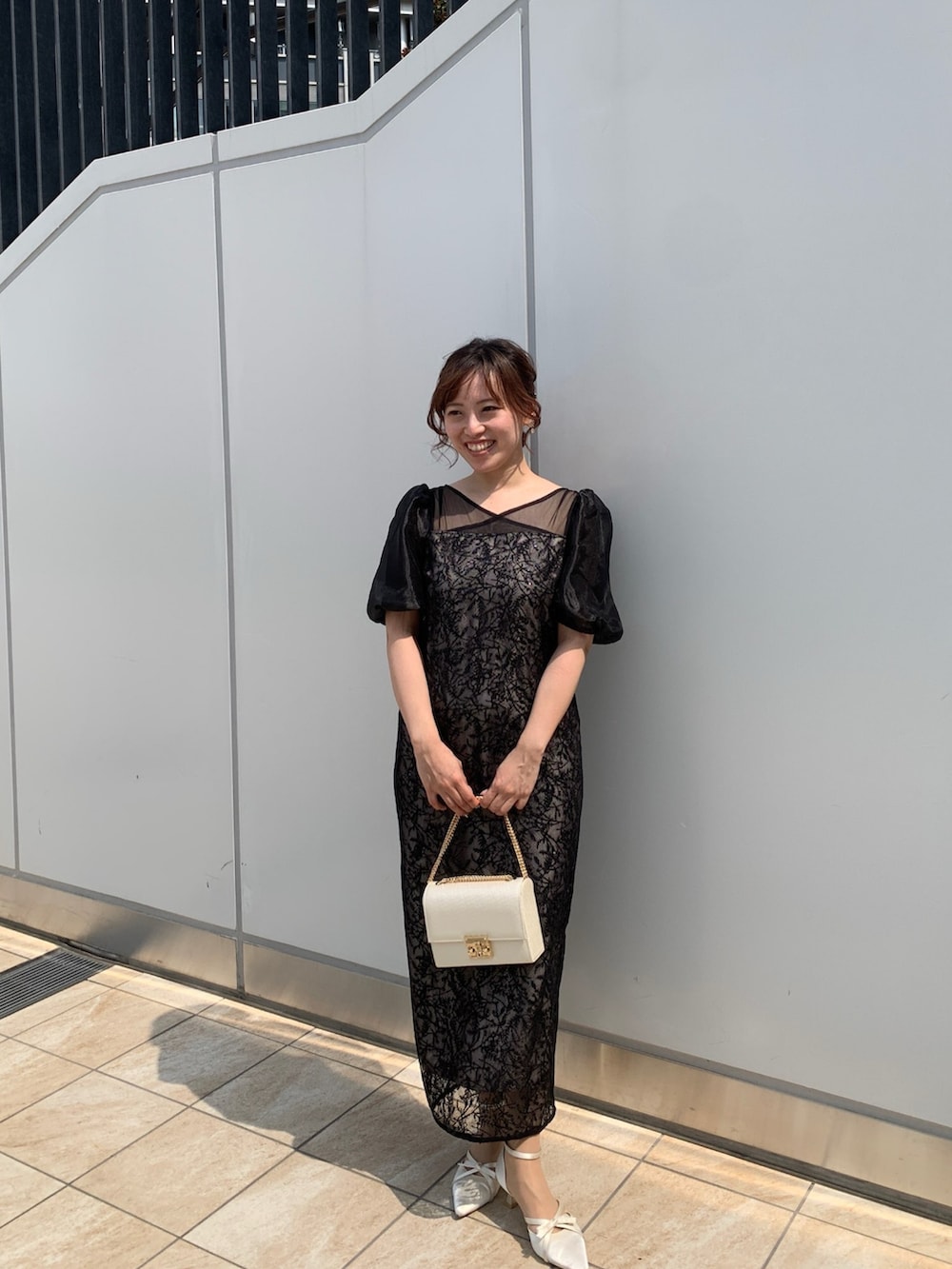 ブラック系のドレス、ブラック系のクラッチバッグ、ベージュ系のパンプスを着用したレディースの春コーディネートの8枚目の写真
