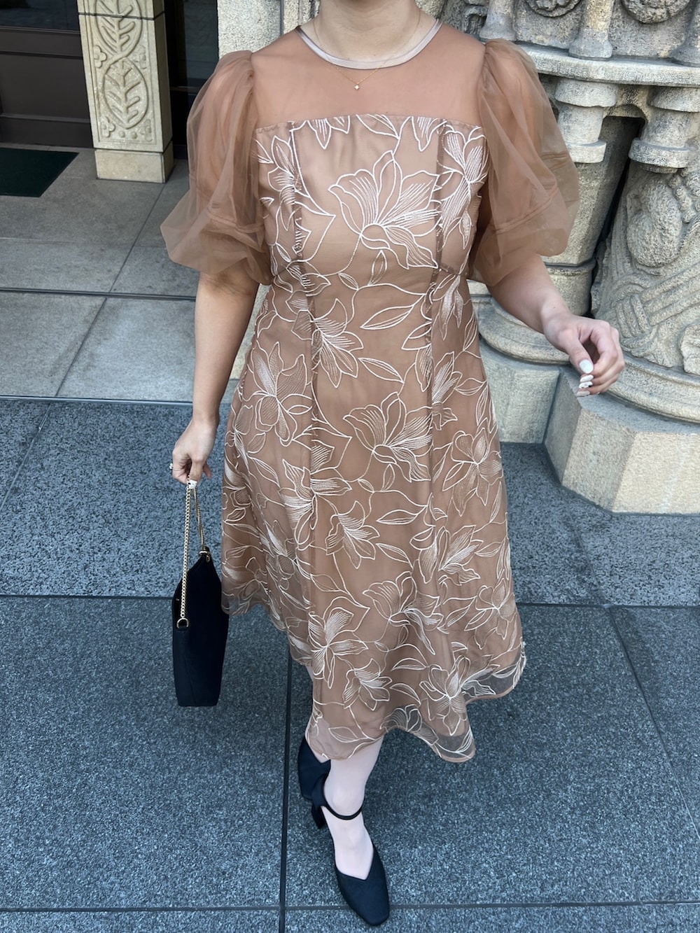 オレンジ系のドレス、ブラック系のパンプス、ブラック系のショルダーバッグを着用したレディースの春コーディネートの3枚目の写真