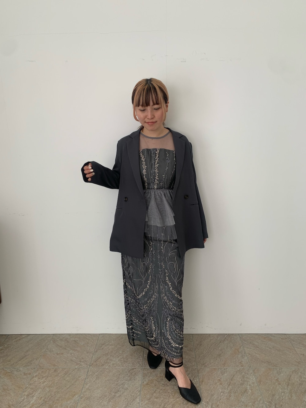 グレー系のドレス、グレー系のジャケット/アウター、ブラック系のパンプスを着用したレディースの春コーディネートの2枚目の写真