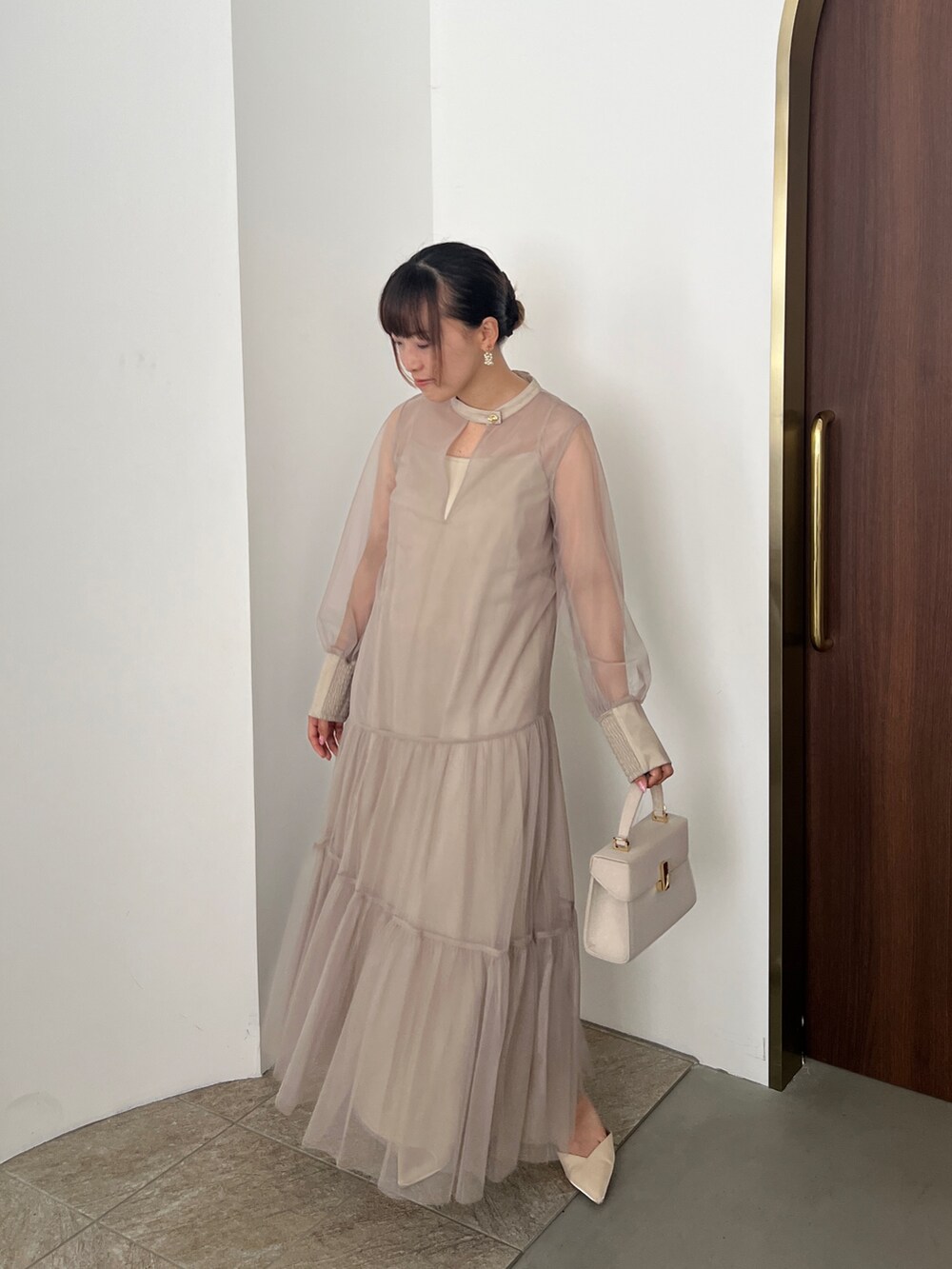 ベージュ系のドレス、ゴールド系のハンドバッグ、ベージュ系のシューズを着用したレディースの秋コーディネートの7枚目の写真