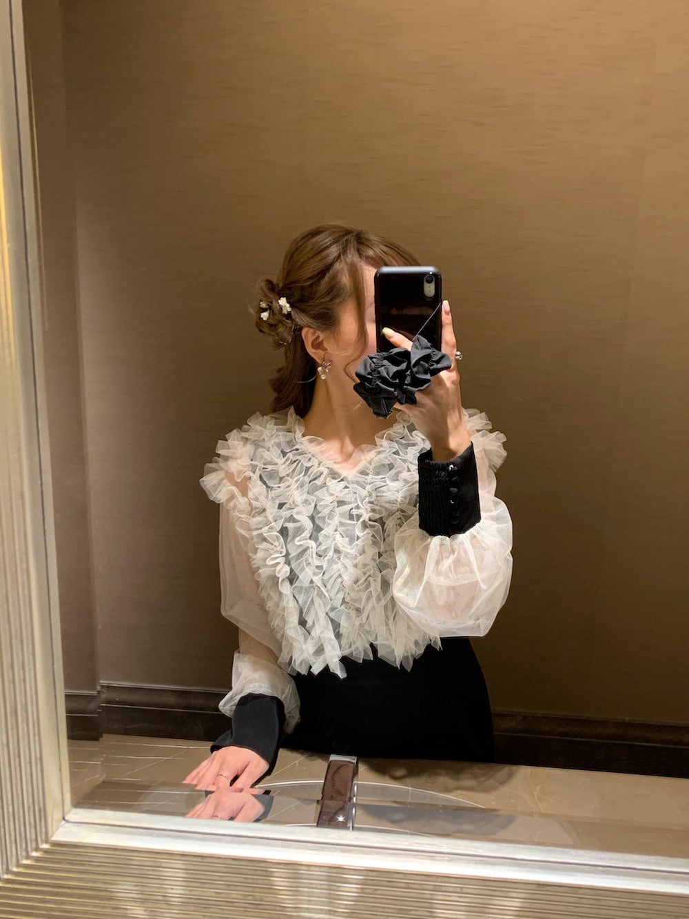 ブラック系のドレス、ブラック系のハンドバッグ、ゴールド系のヘアピンを着用したレディースの春コーディネートの6枚目の写真