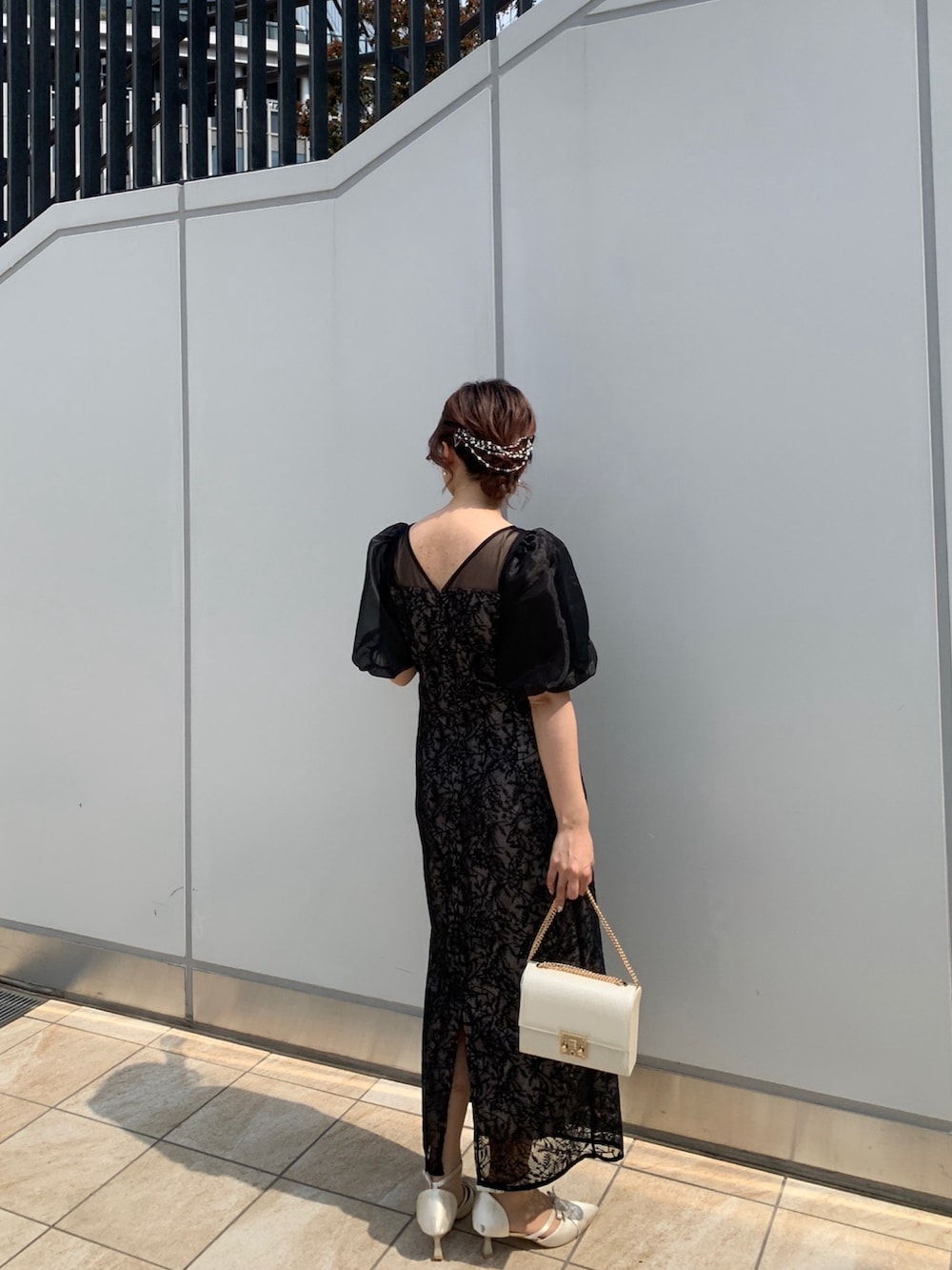 ブラック系のドレス、ブラック系のクラッチバッグ、ベージュ系のパンプスを着用したレディースの春コーディネートの7枚目の写真