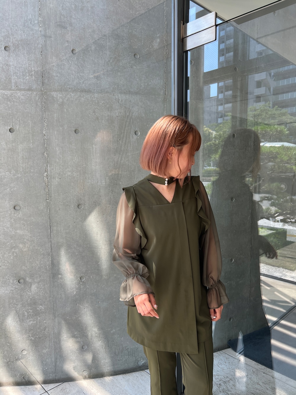 グリーン系のパンツドレス、ブラック系のパンプスを着用したレディースの秋コーディネートの3枚目の写真