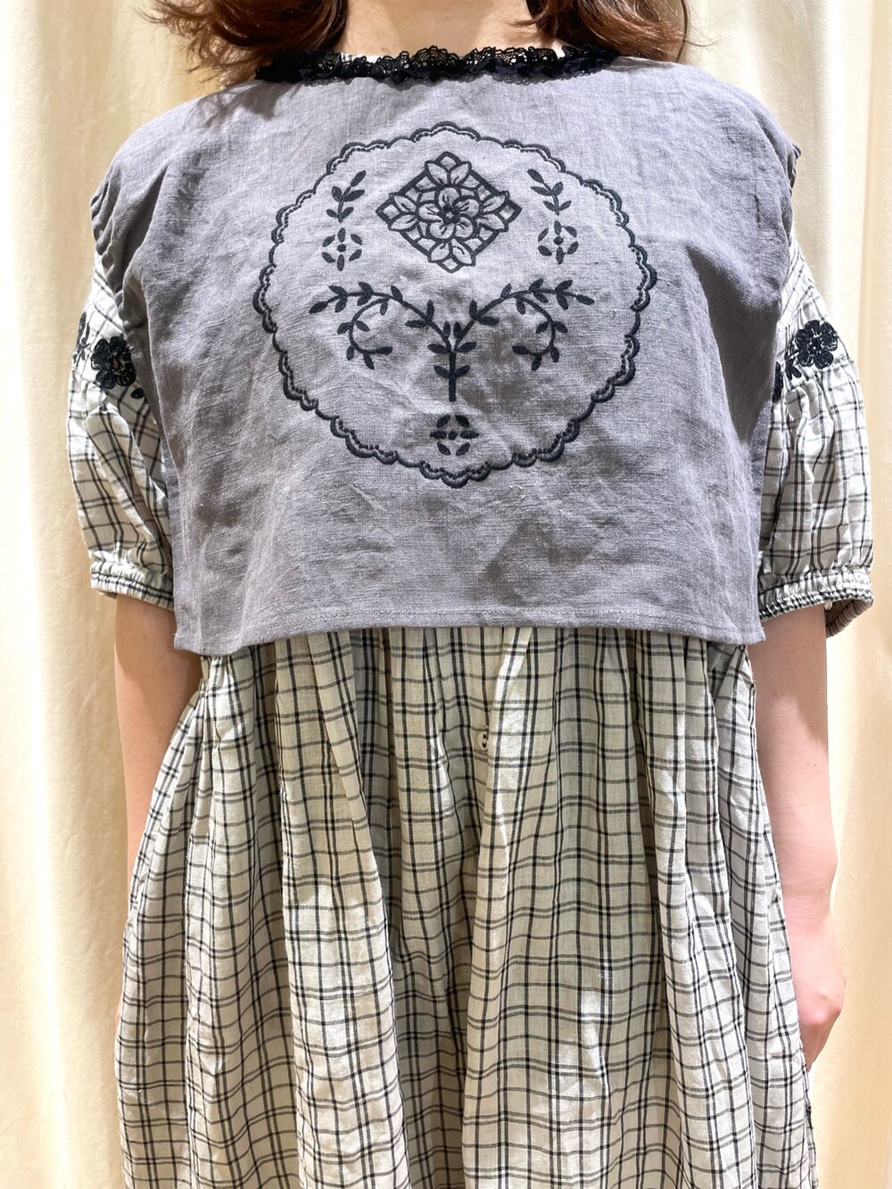 グレー系のベスト、グレー系のワンピース、ホワイト系のスカートを着用したレディースの春コーディネートの4枚目の写真