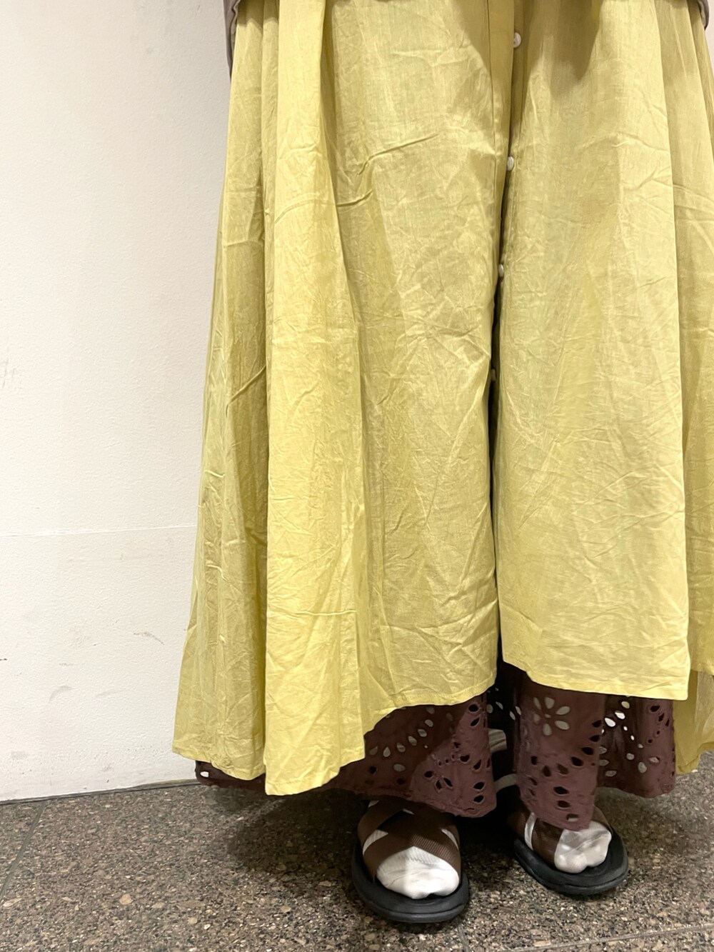 ホワイト系のベスト、イエロー系のワンピース、ブラウン系のスカートを着用したレディースの夏コーディネートの5枚目の写真