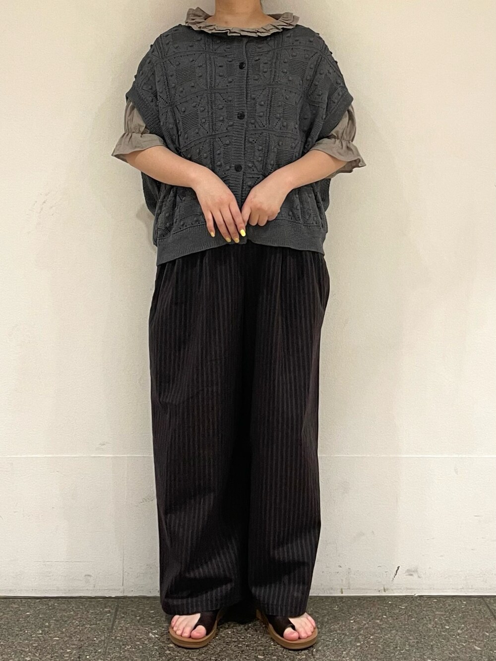 ブラウン系のサンダル、ベージュ系のシャツ/ブラウス、グレー系のベストを着用したレディースの秋コーディネートの2枚目の写真