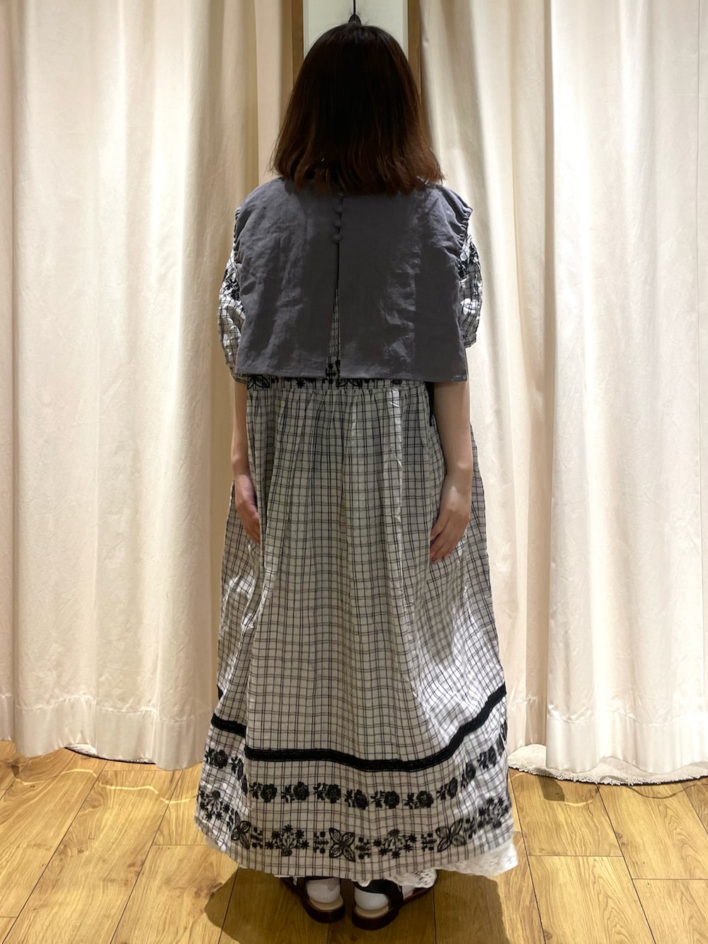 グレー系のベスト、グレー系のワンピース、ホワイト系のスカートを着用したレディースの春コーディネートの3枚目の写真