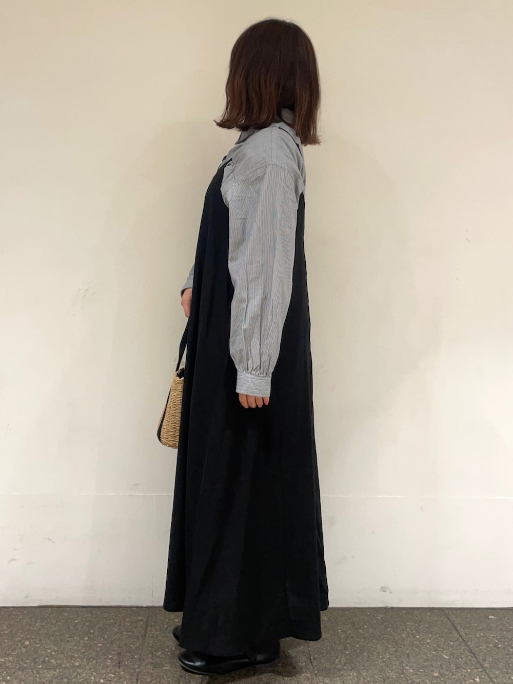 ブルー系のチュニック、ブラック系のワンピース、ブラック系のハンドバッグを着用したレディースの春コーディネートの3枚目の写真