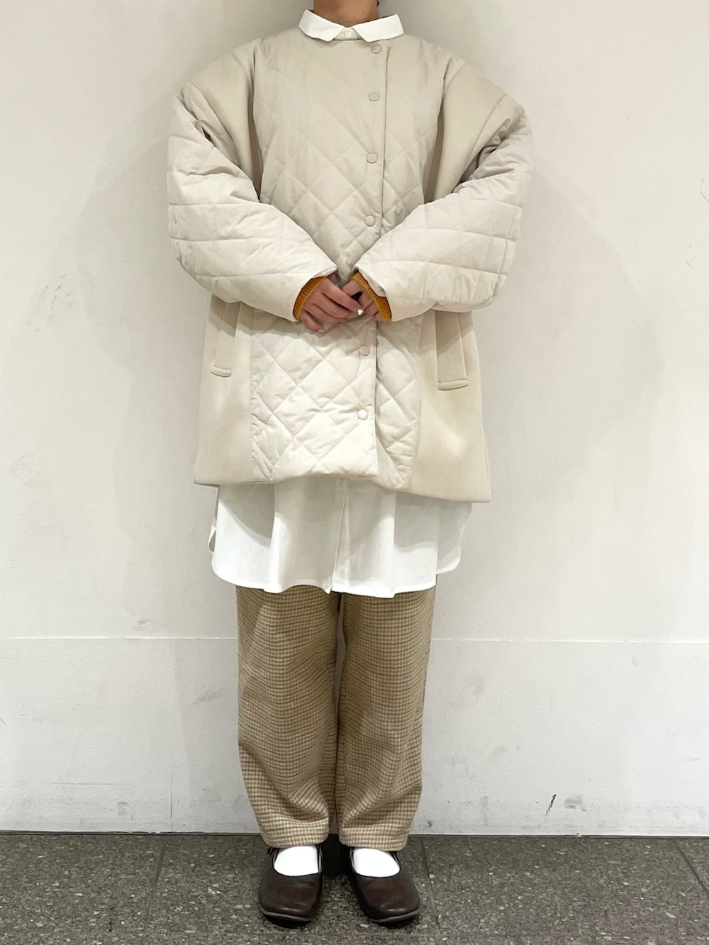 ブラウン系のドレスシューズ、ホワイト系のチュニック、ホワイト系のブルゾンを着用したレディースの冬コーディネートの2枚目の写真