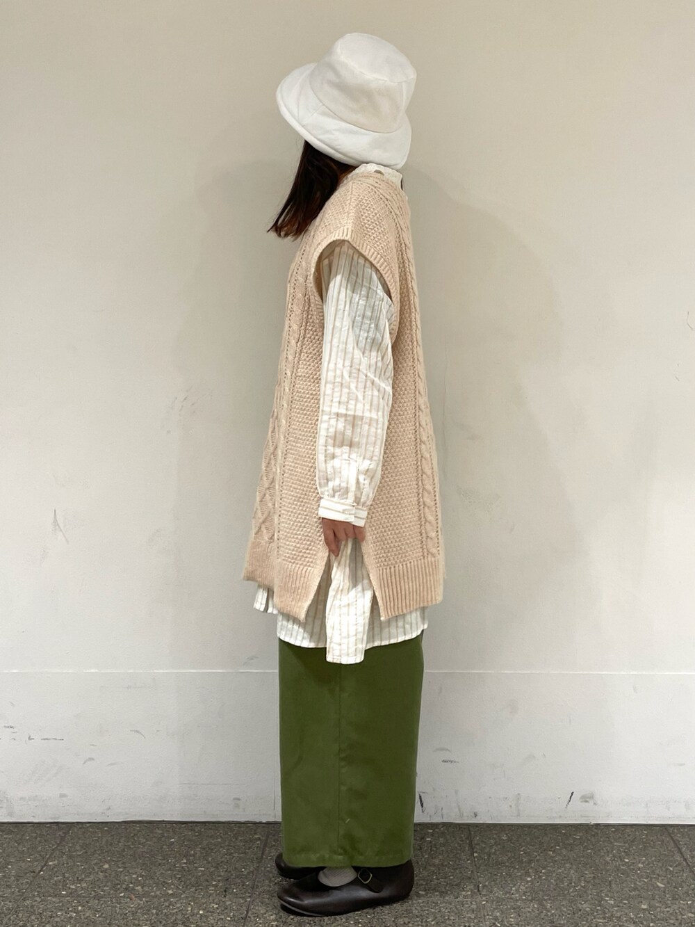 ブラウン系のドレスシューズ、ホワイト系のベスト、ベージュ系のチュニックを着用したレディースの冬コーディネートの3枚目の写真