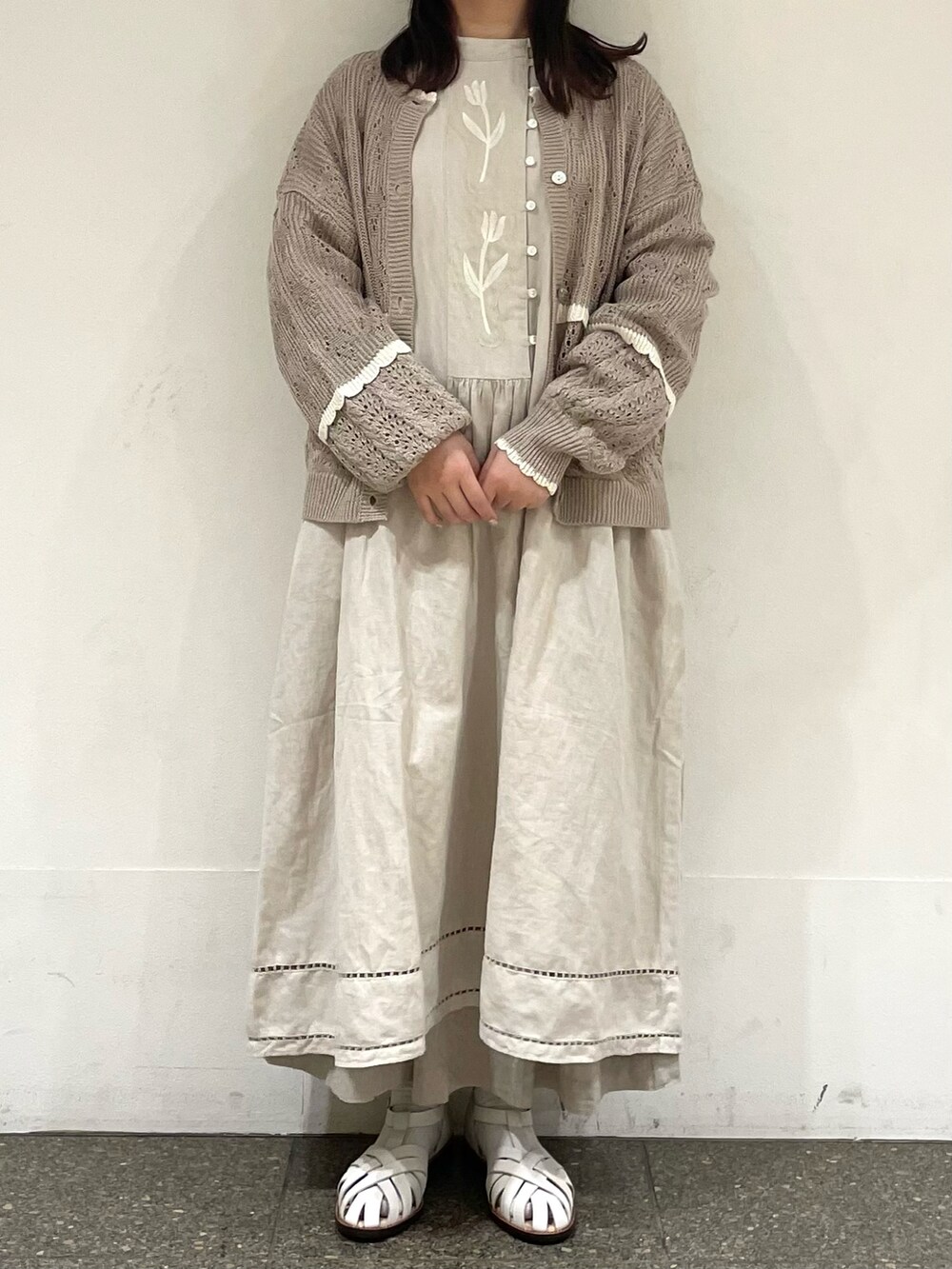 ホワイト系のサンダル、ベージュ系のカーディガン/ボレロ、グレー系のワンピースを着用したレディースの春コーディネートの2枚目の写真