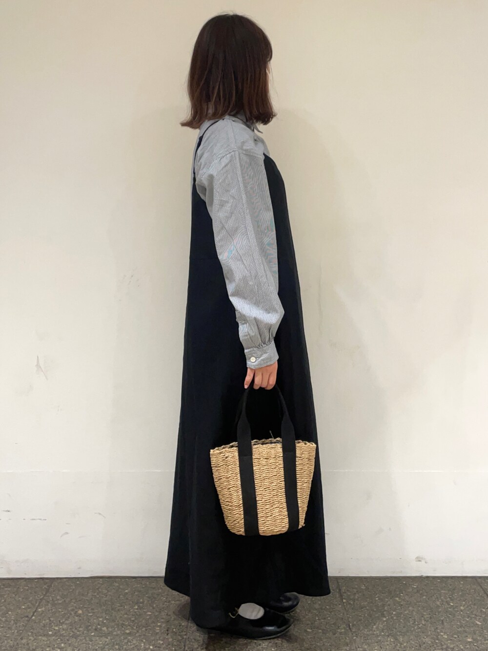 ブルー系のチュニック、ブラック系のワンピース、ブラック系のハンドバッグを着用したレディースの春コーディネートの5枚目の写真