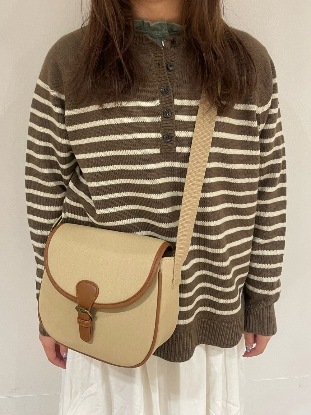 グリーン系のシャツ/ブラウス、ブラウン系のニット/セーター、ベージュ系のショルダーバッグを着用したレディースの冬コーディネートの4枚目の写真