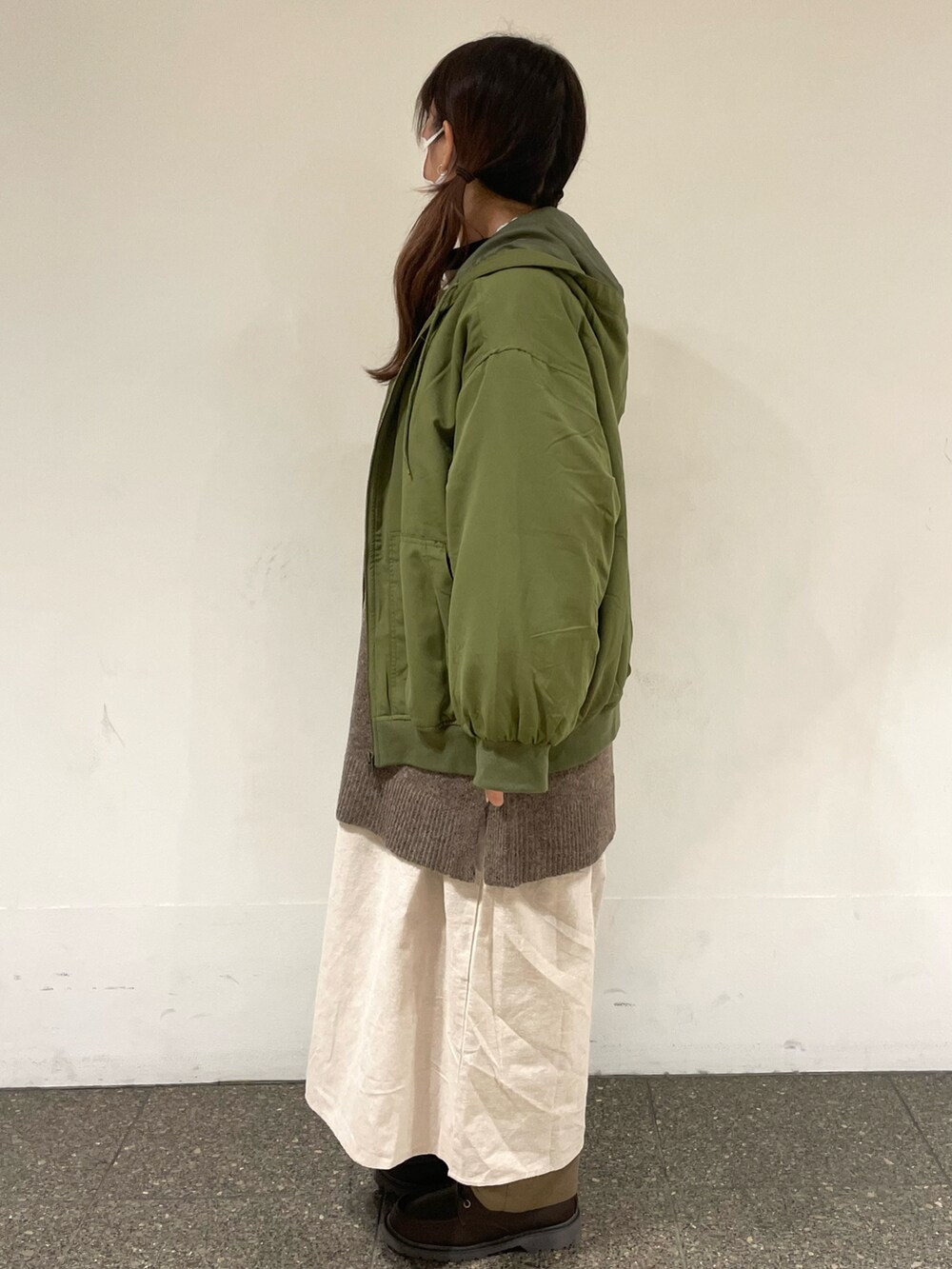 ベージュ系のワンピース、グリーン系のブルゾン、ブラウン系のベストを着用したレディースの冬コーディネートの2枚目の写真