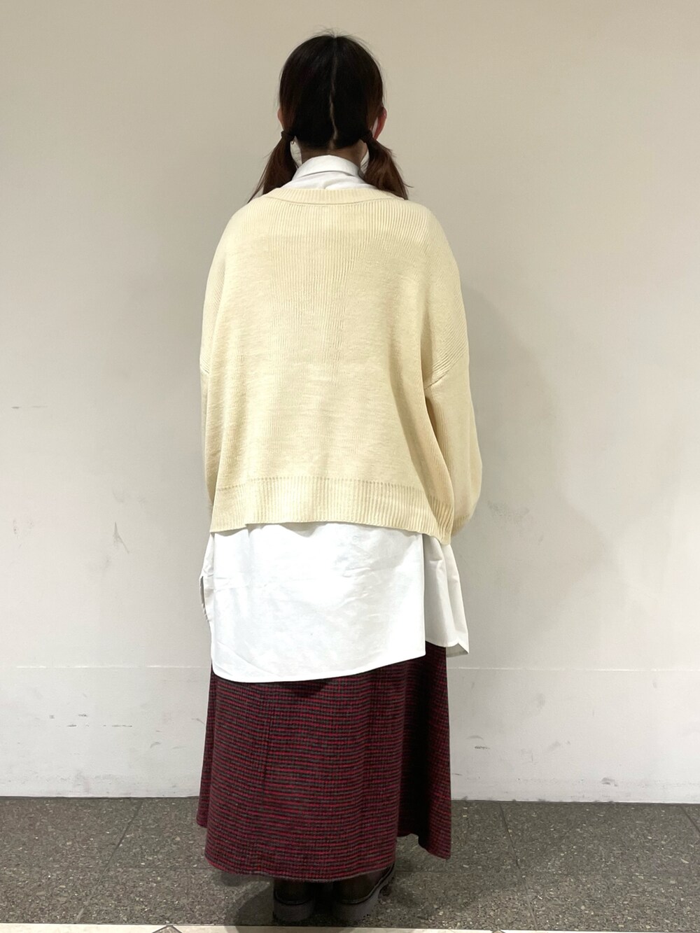 レッド系のスカート、ブラウン系のブーツ、ホワイト系のチュニックを着用したレディースの冬コーディネートの3枚目の写真