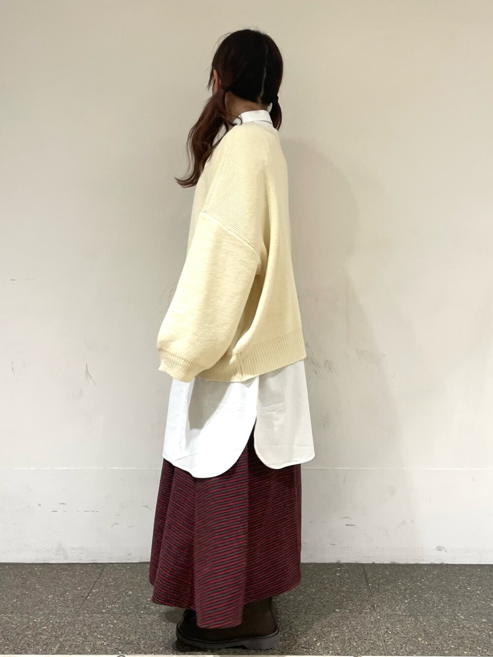 レッド系のスカート、ブラウン系のブーツ、ホワイト系のチュニックを着用したレディースの冬コーディネートの2枚目の写真