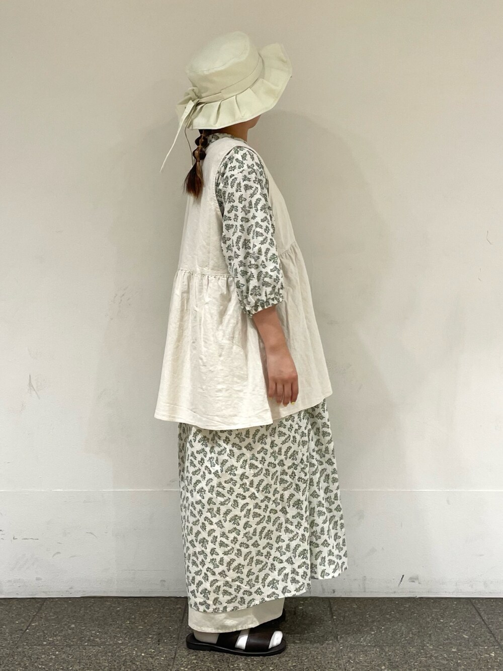 ブラウン系のサンダル、ホワイト系のワンピース、ホワイト系のベストを着用したレディースの秋コーディネートの5枚目の写真