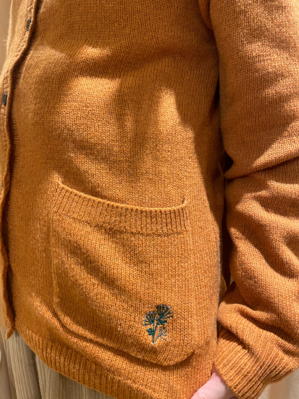 ベージュ系のチュニック、オレンジ系のカーディガン/ボレロ、ホワイト系のトートバッグを着用したレディースの秋コーディネートの5枚目の写真