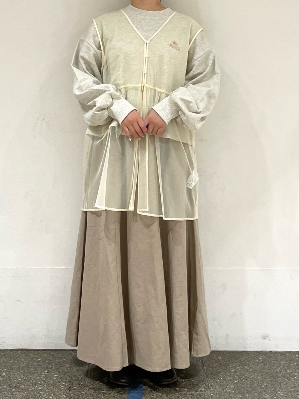 グレー系のTシャツ/カットソー、ホワイト系のベスト、ベージュ系のスカートを着用したレディースの秋コーディネートの2枚目の写真