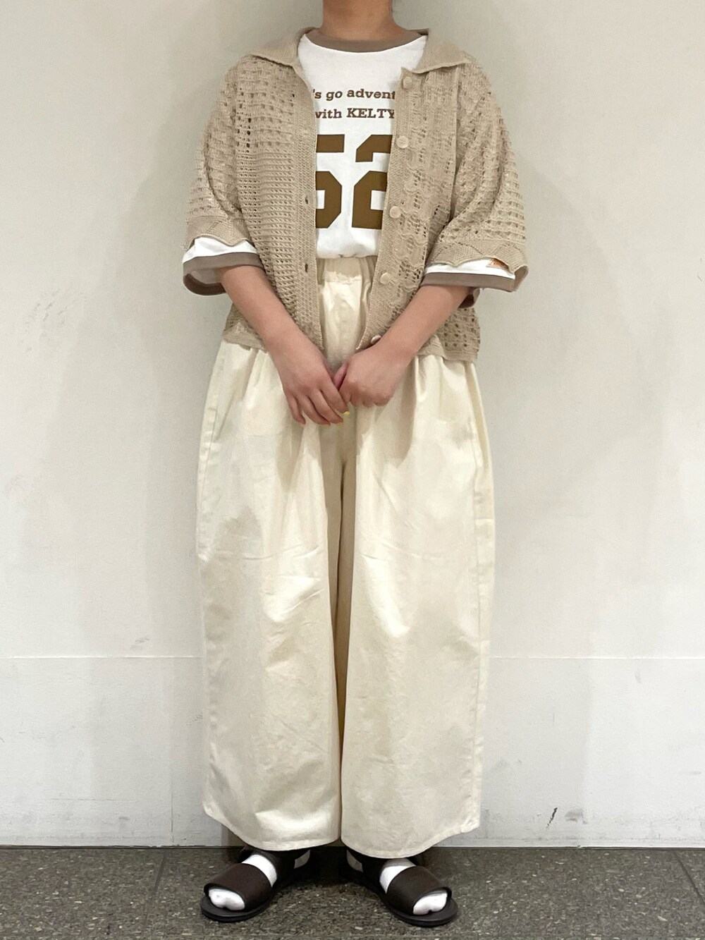 ブラウン系のサンダル、ベージュ系のTシャツ/カットソー、ホワイト系のカーディガン/ボレロを着用したレディースの秋コーディネートの2枚目の写真