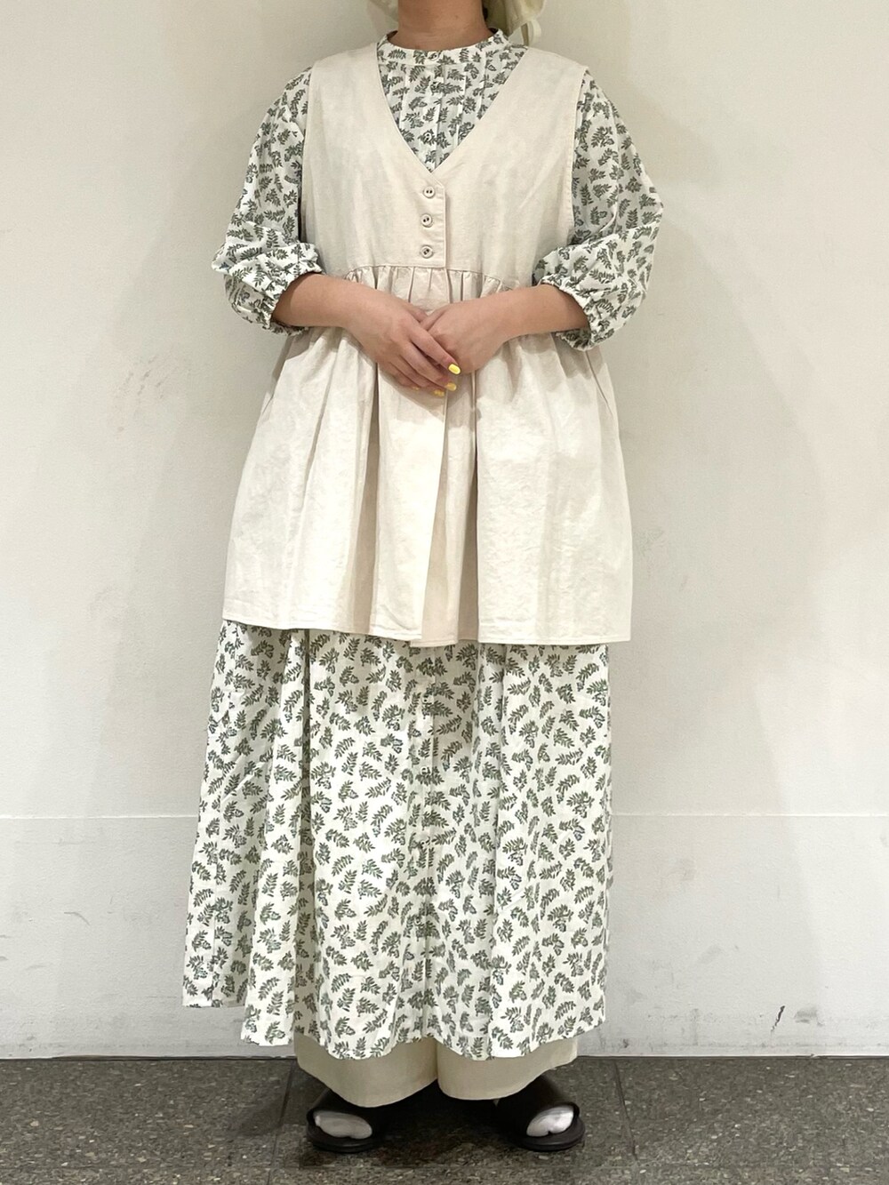 ブラウン系のサンダル、ホワイト系のワンピース、ホワイト系のベストを着用したレディースの秋コーディネートの2枚目の写真