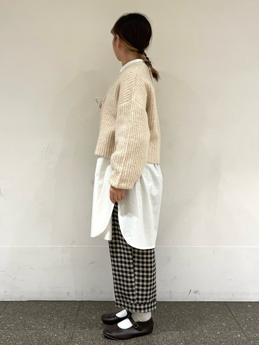 ホワイト系のチュニック、ブラウン系のドレスシューズ、ホワイト系のカーディガン/ボレロを着用したレディースの冬コーディネートの3枚目の写真