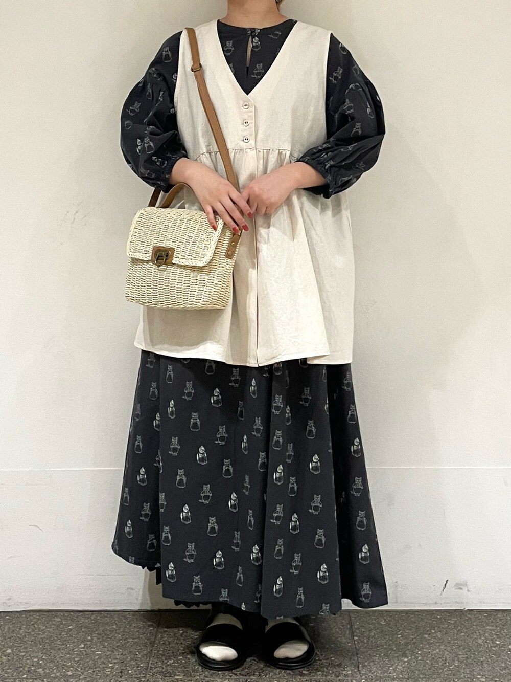 ブラック系のサンダル、ブラック系のワンピース、ホワイト系のハンドバッグを着用したレディースの夏コーディネートの2枚目の写真