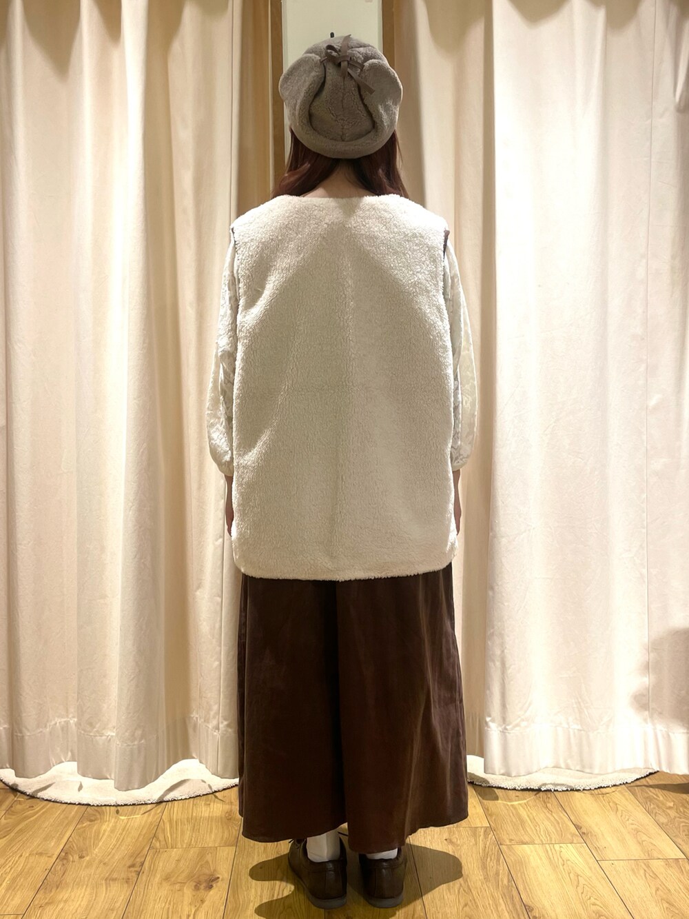 ホワイト系のTシャツ/カットソー、ホワイト系のベスト、ブラウン系のジャンパースカートを着用したレディースの秋コーディネートの3枚目の写真