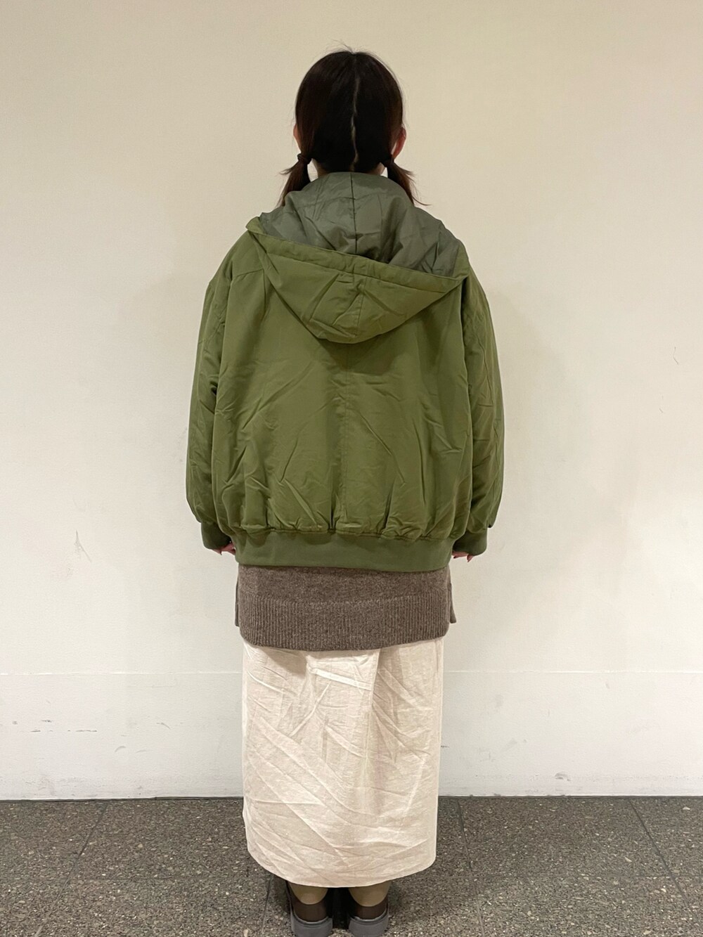 ベージュ系のワンピース、グリーン系のブルゾン、ブラウン系のベストを着用したレディースの冬コーディネートの3枚目の写真