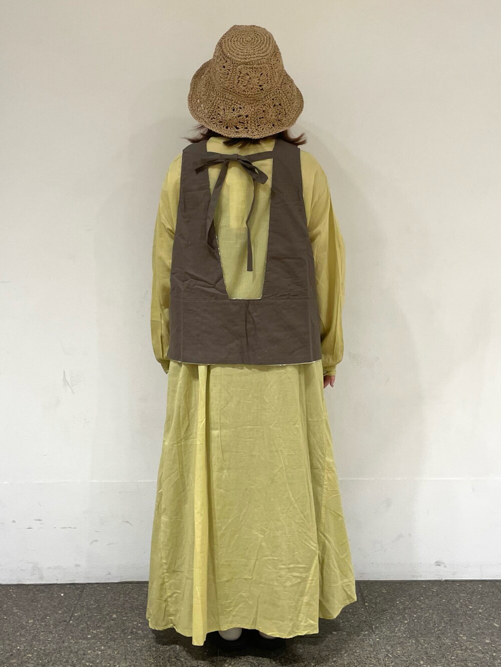 ホワイト系のベスト、イエロー系のワンピース、ブラウン系のスカートを着用したレディースの夏コーディネートの3枚目の写真