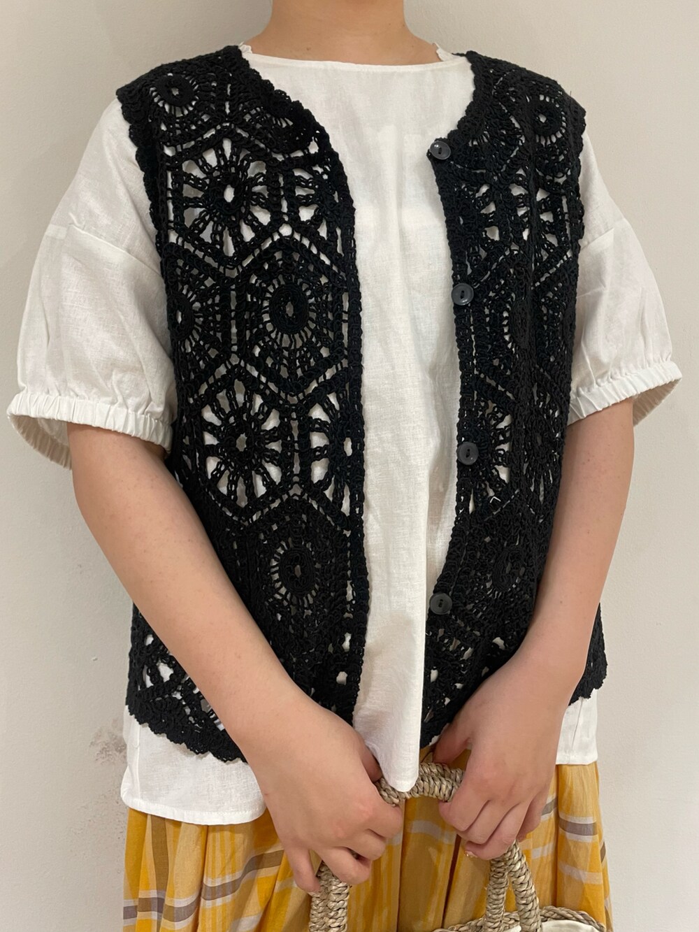 ブラック系のサンダル、ホワイト系のかごバッグ、ホワイト系のTシャツ/カットソーを着用したレディースの夏コーディネートの4枚目の写真