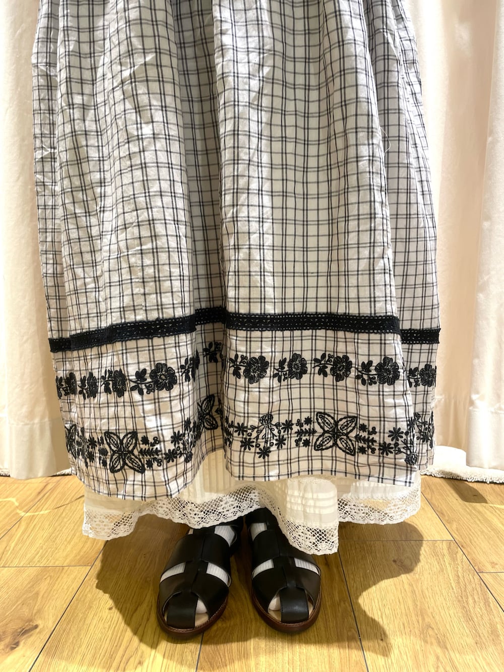 グレー系のベスト、グレー系のワンピース、ホワイト系のスカートを着用したレディースの春コーディネートの5枚目の写真