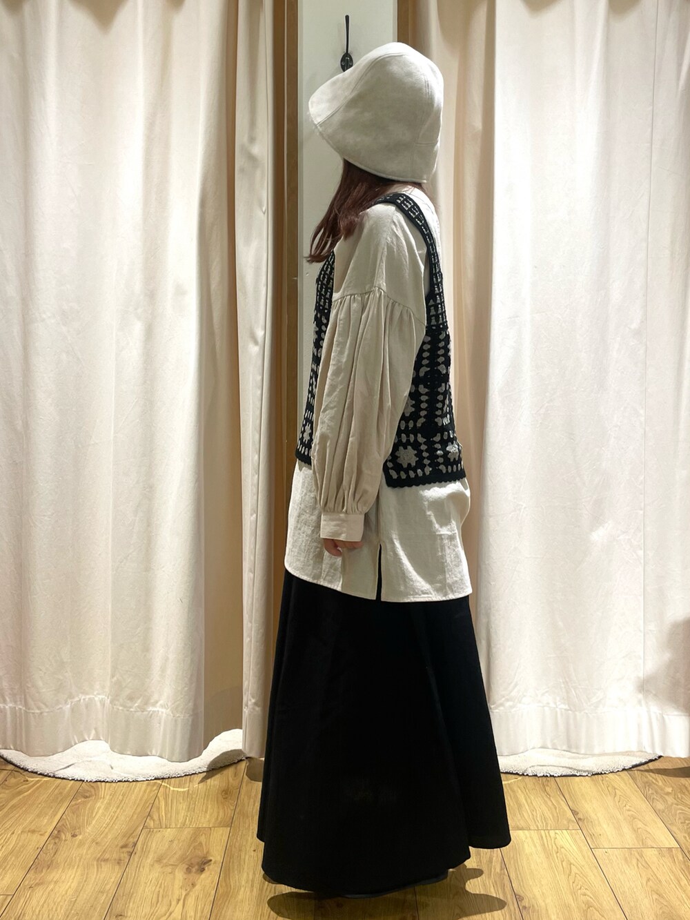 ベージュ系のチュニック、ブラック系のベスト、ブラック系のスカートを着用したレディースの秋コーディネートの2枚目の写真