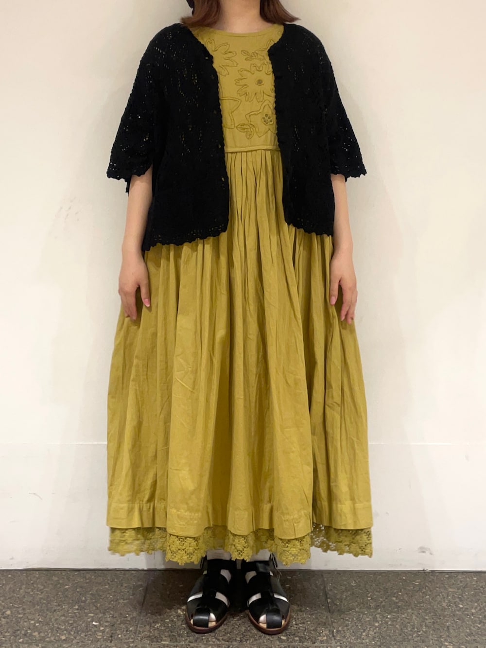 ブラック系のカーディガン/ボレロ、グリーン系のワンピース、ブラック系のサンダルを着用したレディースの春コーディネートの2枚目の写真