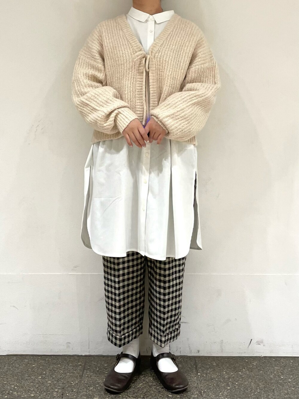 ホワイト系のチュニック、ブラウン系のドレスシューズ、ホワイト系のカーディガン/ボレロを着用したレディースの冬コーディネートの2枚目の写真