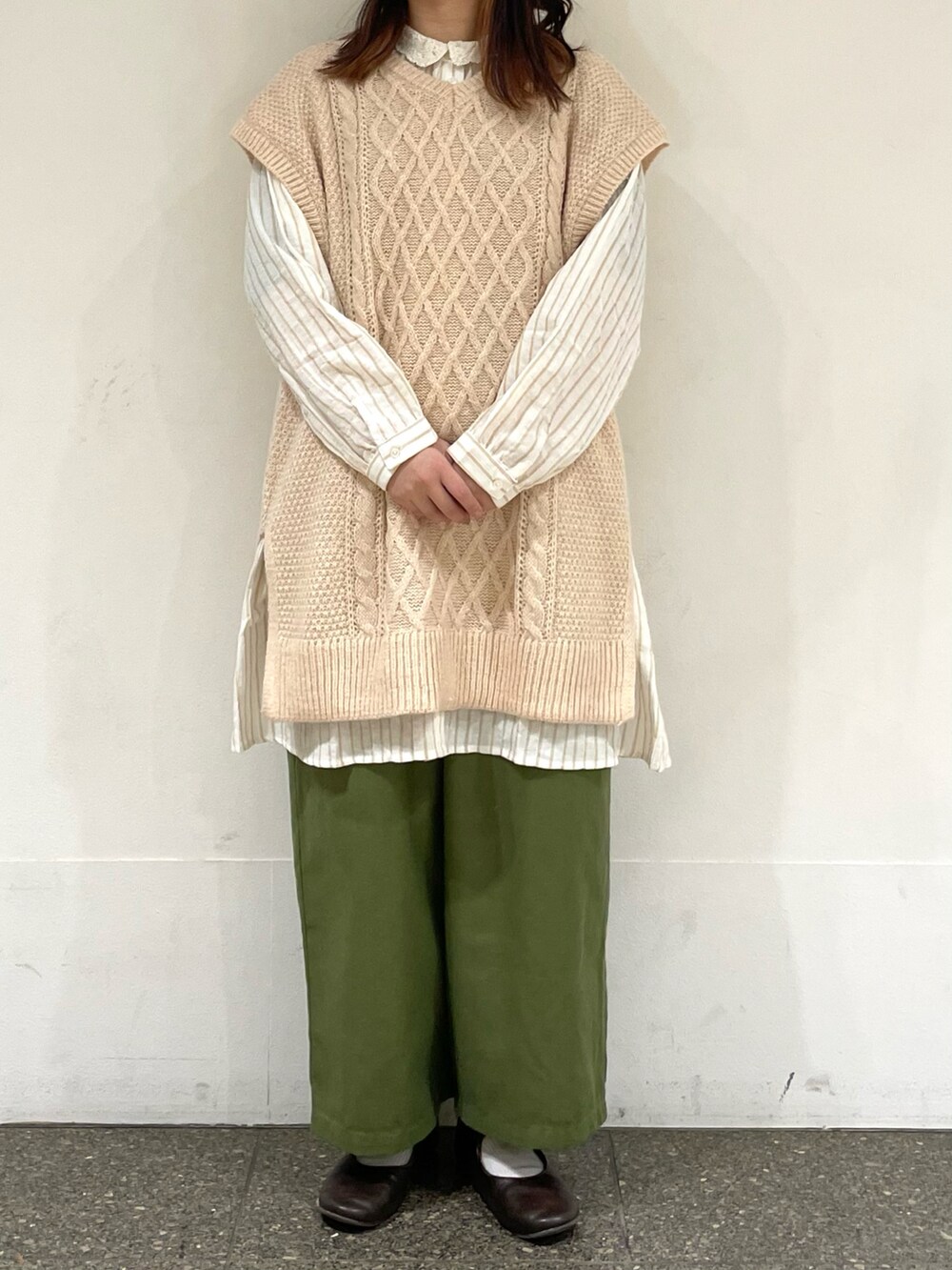 ブラウン系のドレスシューズ、ホワイト系のベスト、ベージュ系のチュニックを着用したレディースの冬コーディネートの2枚目の写真