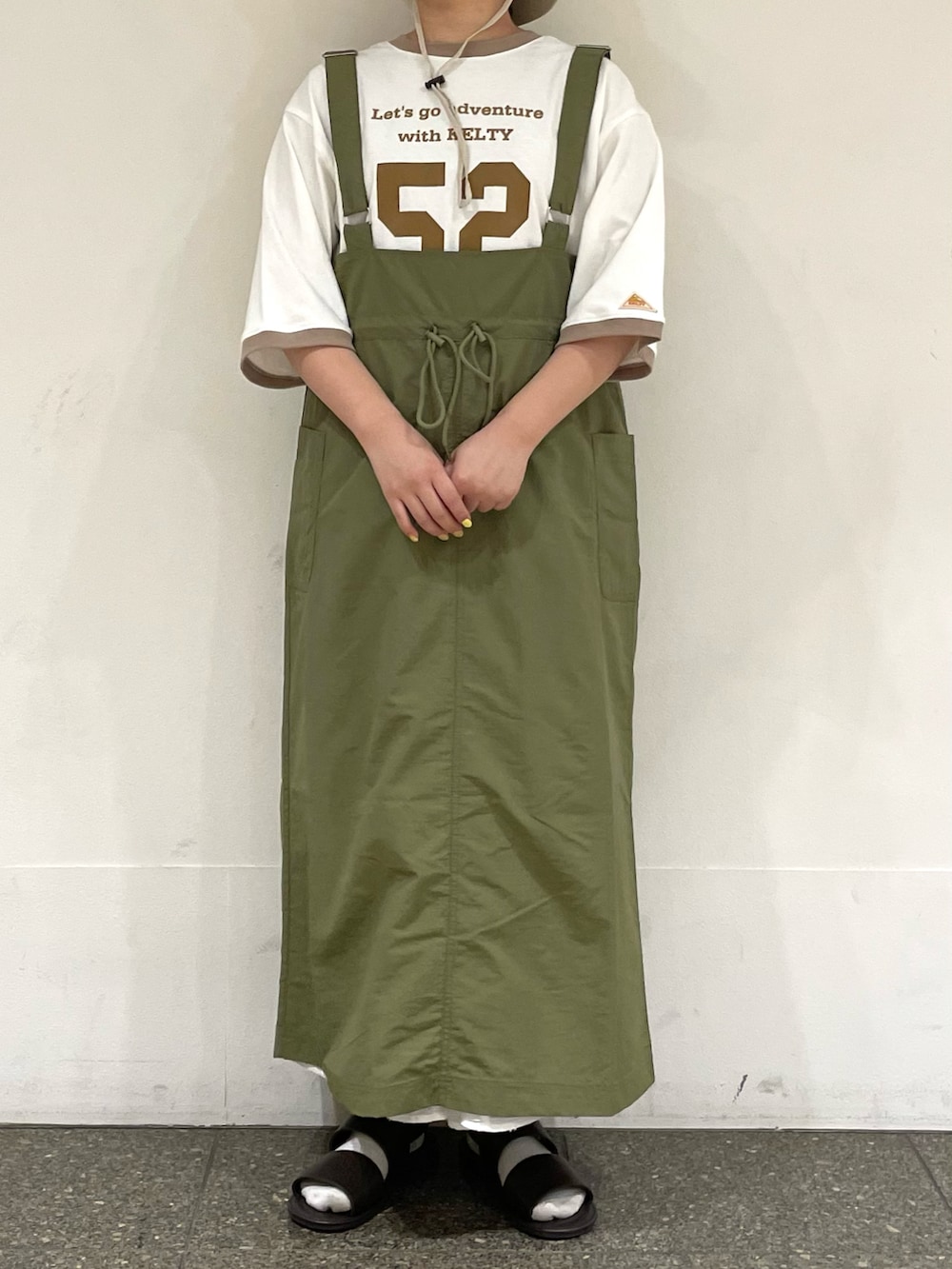 ブラウン系のサンダル、ベージュ系のTシャツ/カットソー、グリーン系のスカートを着用したレディースの秋コーディネートの2枚目の写真