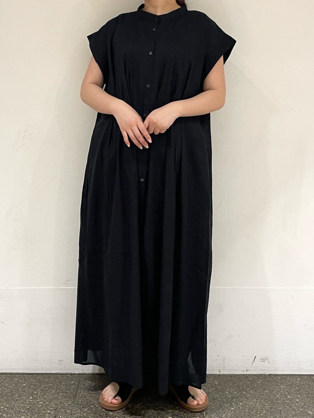 ブラウン系のサンダル、ブラック系のワンピースを着用したレディースの秋コーディネートの2枚目の写真