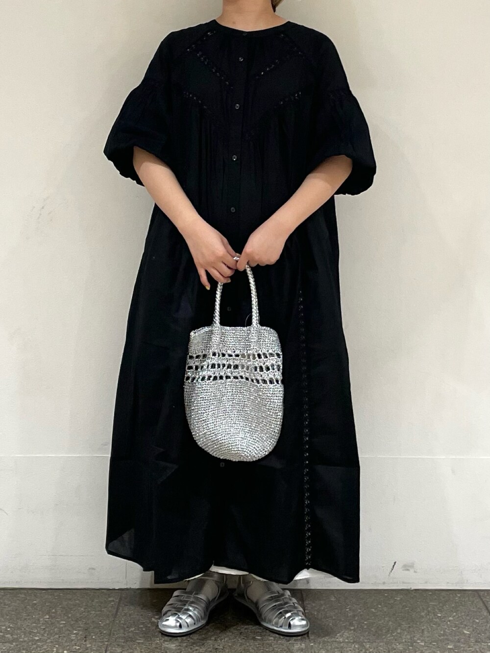 シルバー系のサンダル、ブラック系のワンピース、シルバー系のハンドバッグを着用したレディースの夏コーディネートの2枚目の写真