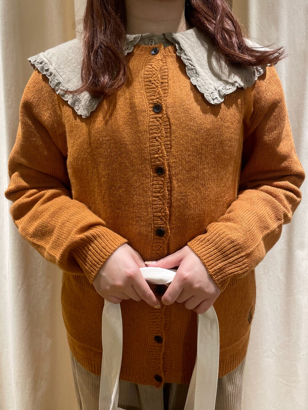 ベージュ系のチュニック、オレンジ系のカーディガン/ボレロ、ホワイト系のトートバッグを着用したレディースの秋コーディネートの4枚目の写真